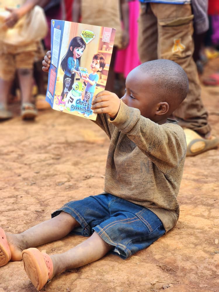 A young child holding a Rhapsody of Realities Early Reader